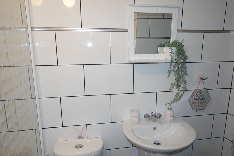 Bathroom with white subway tile wall, two round sinks, mirror, and small decorative items