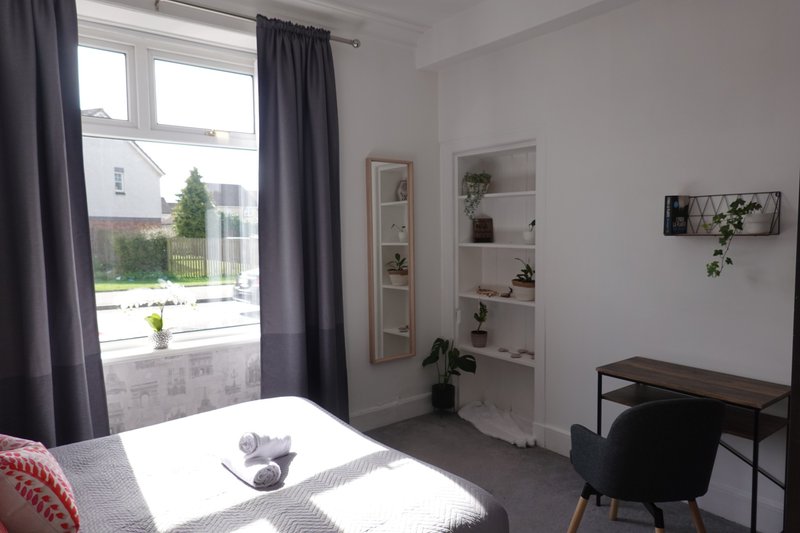 Bright bedroom with double bed, desk, shelving unit and window with garden view