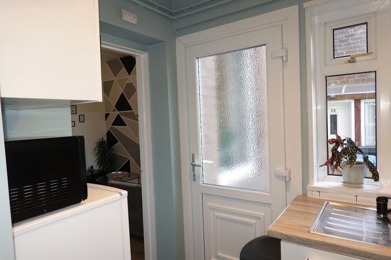 Modern kitchen with blue-grey walls, white cabinetry, wooden worktop and frosted glass door