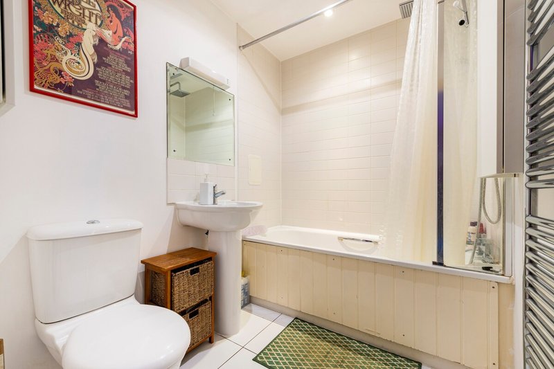 Bright bathroom with toilet, sink, mirror, bathtub and decorative wall art