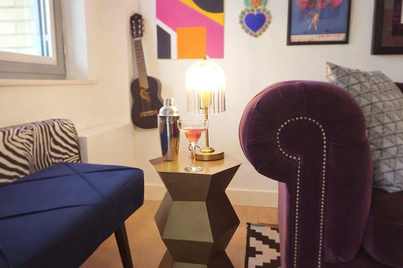 Living room with blue sofa, purple armchair, guitar, and colorful wall art