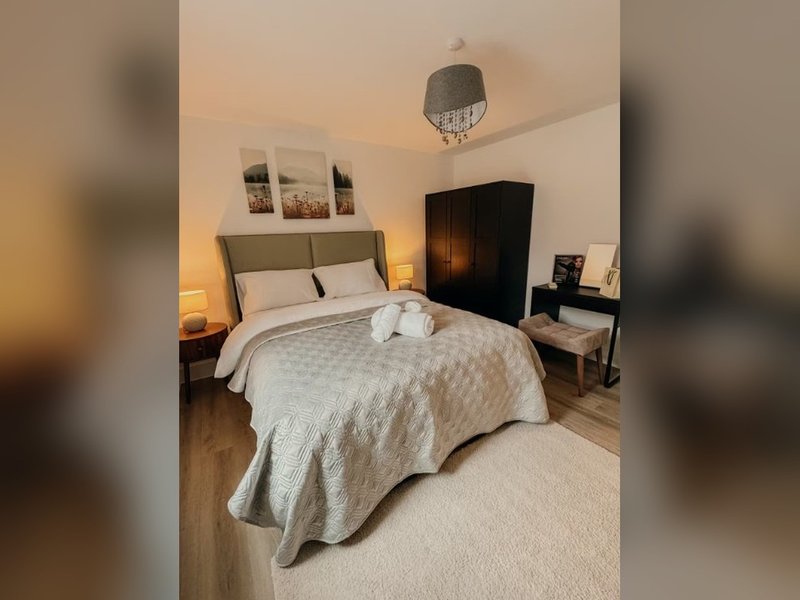 Bedroom with double bed, headboard, ceiling light, bedside tables and wooden floor