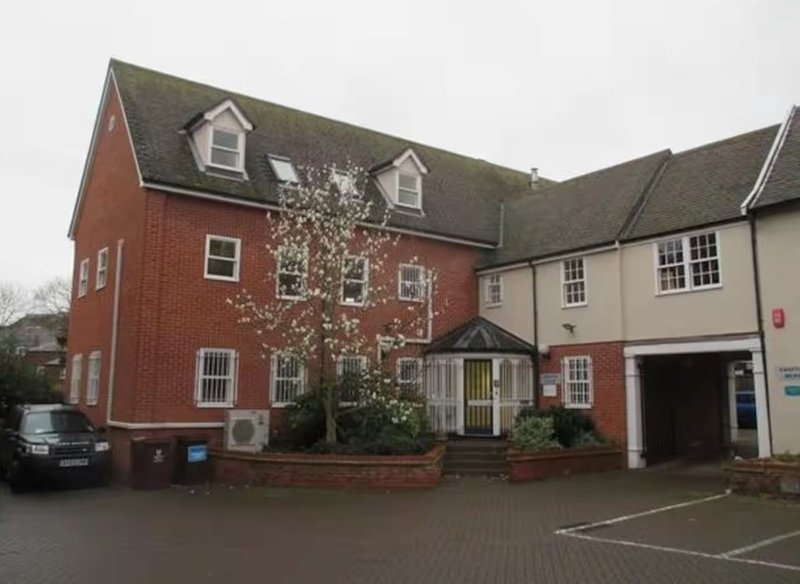 Large brick residential building with multiple units, driveway and front entrance