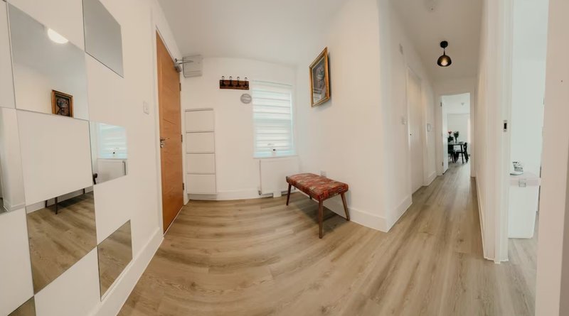 Bright hallway with wooden flooring, white walls, interior doors and small bench seating