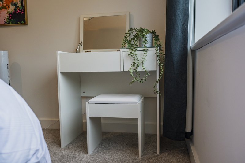Bedroom dressing table with mirror, stool, and potted plant decoration