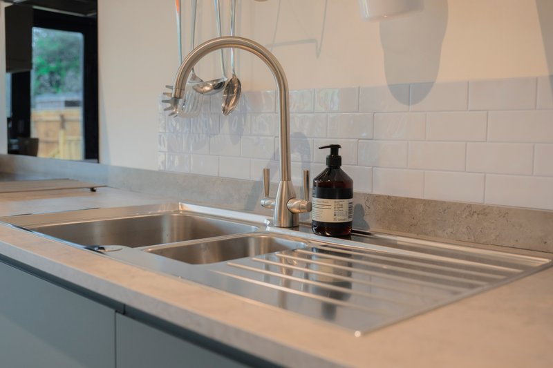 Modern kitchen sink with stainless steel drainer, chrome tap and white subway tile splashback