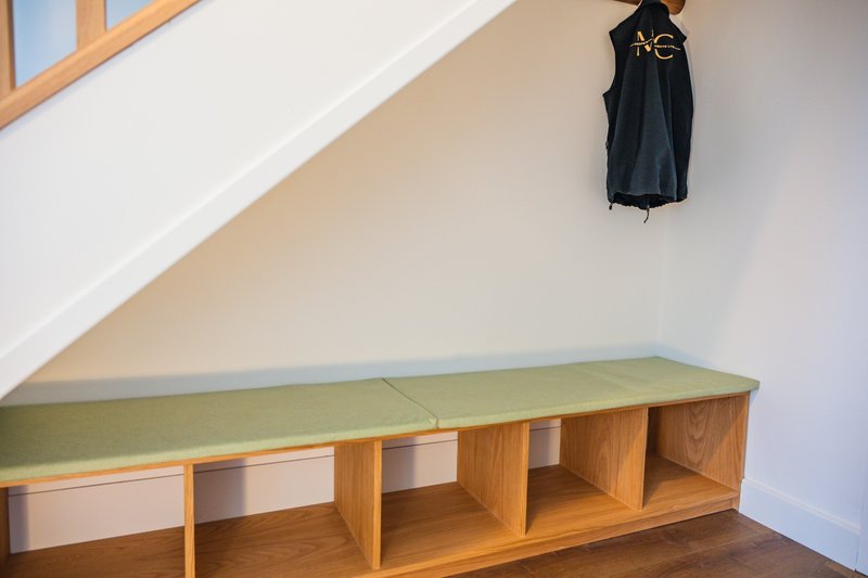 Attic storage space with wooden bench seating and black jacket hanging on wall