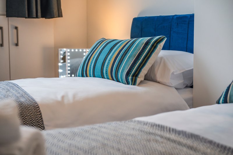 Bedroom with two beds, striped pillows, blue headboard and vanity mirror