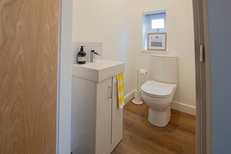 Clean bathroom with toilet, sink vanity, yellow towel and small window