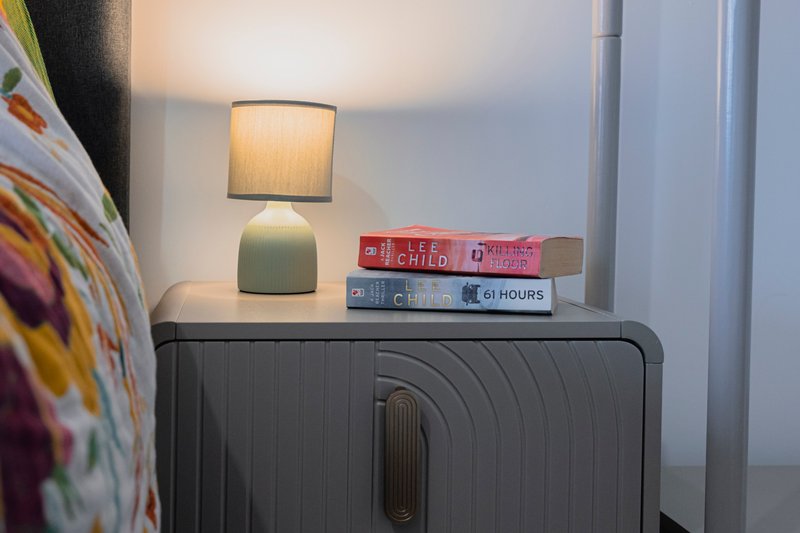 Bedroom nightstand with lamp, decorative objects, and stacked books