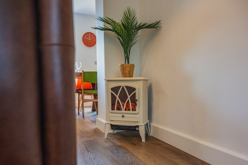 Hallway with wood stove, potted plant, and view into adjoining room