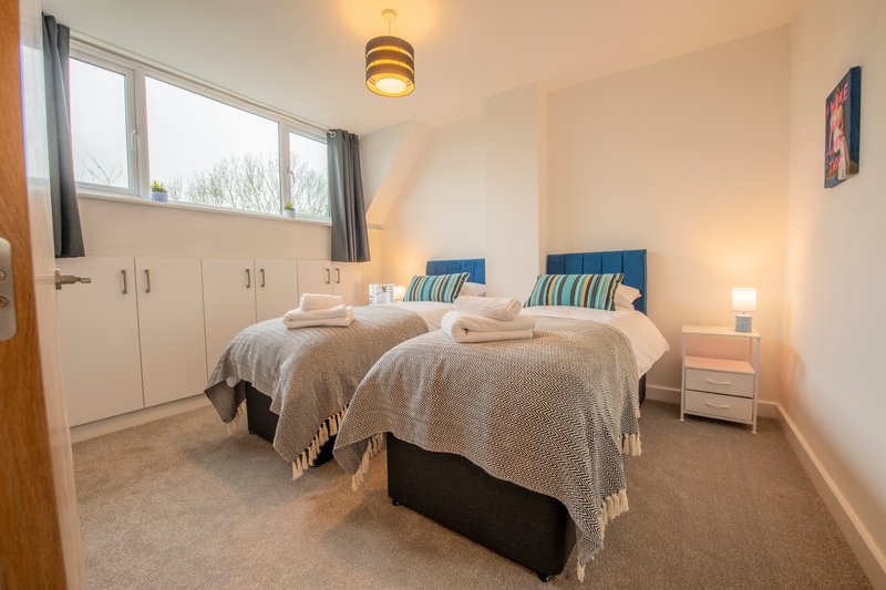 Bright bedroom with two single beds, built-in wardrobes, and large window with countryside views