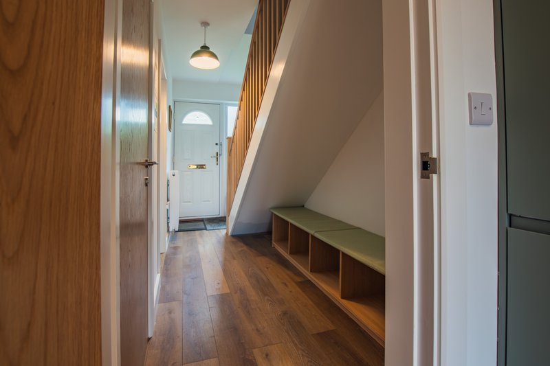 Hallway with wooden flooring, built-in bench seating, and view toward entrance door