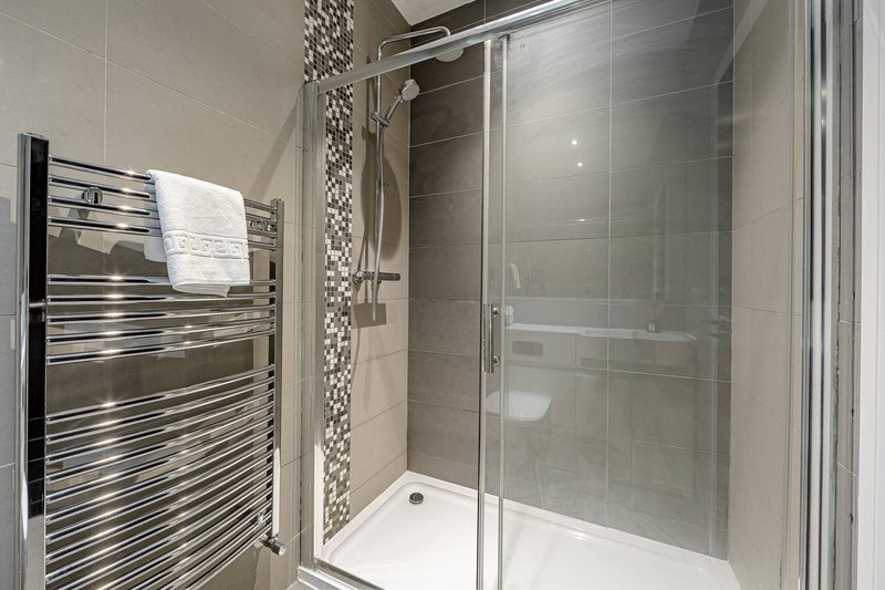 Modern bathroom with walk-in shower, heated towel rail and grey tile walls