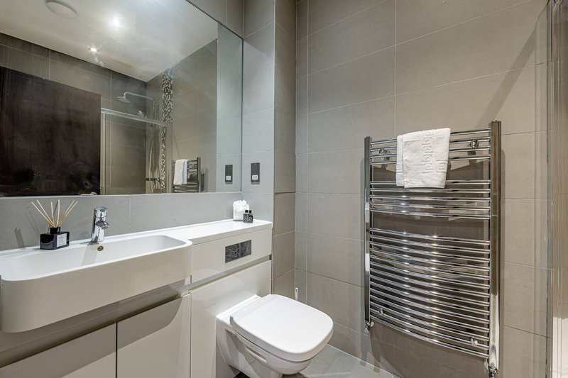 Modern bathroom with white sink, toilet, heated towel rail and large mirror