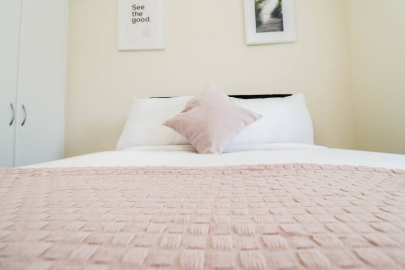 Bedroom with double bed, pink bedding, white pillows and wall art