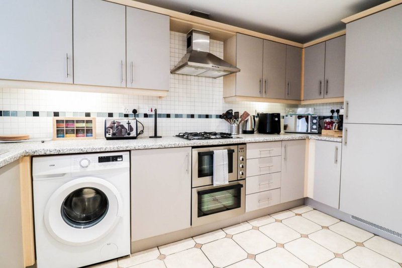 Modern kitchen with white cabinetry, integrated appliances, tiled backsplash and cream floor tiles