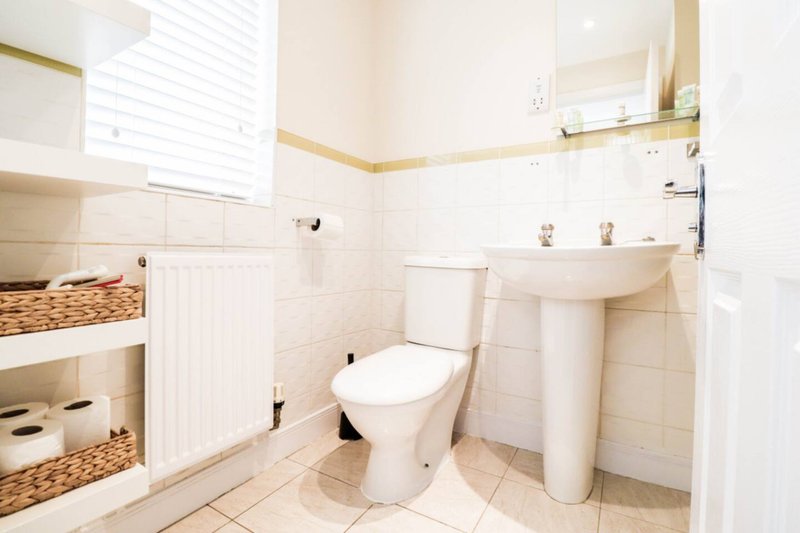 Bathroom with toilet, pedestal sink, mirror, towel rail and built-in storage shelving