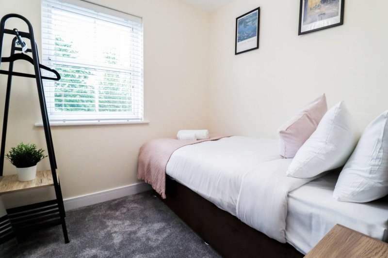 Bright bedroom with twin beds, white bedding, pink pillows and dark headboard