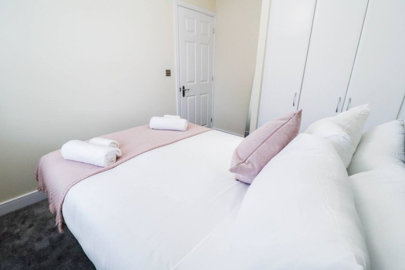 Bedroom with two single beds, white bedding, pink accent runner, and built-in wardrobe