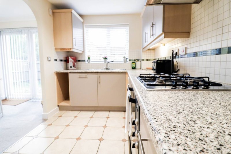 Modern kitchen with cream cabinets, granite countertops, gas hob and tiled flooring