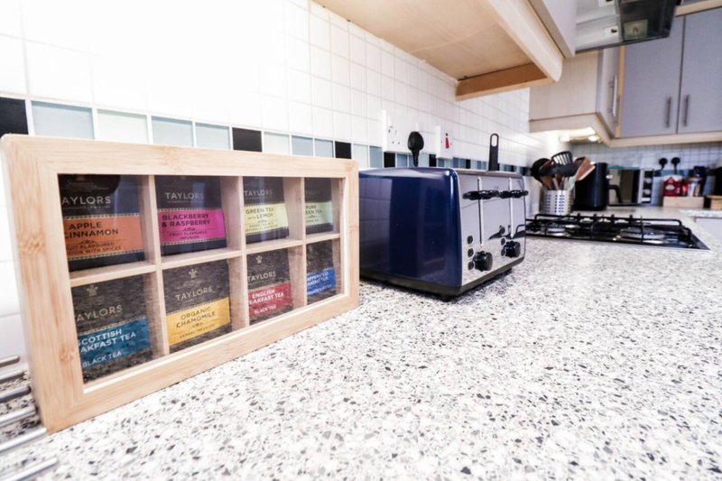 Modern kitchen with speckled countertop, wooden shelving unit with books, and black appliances