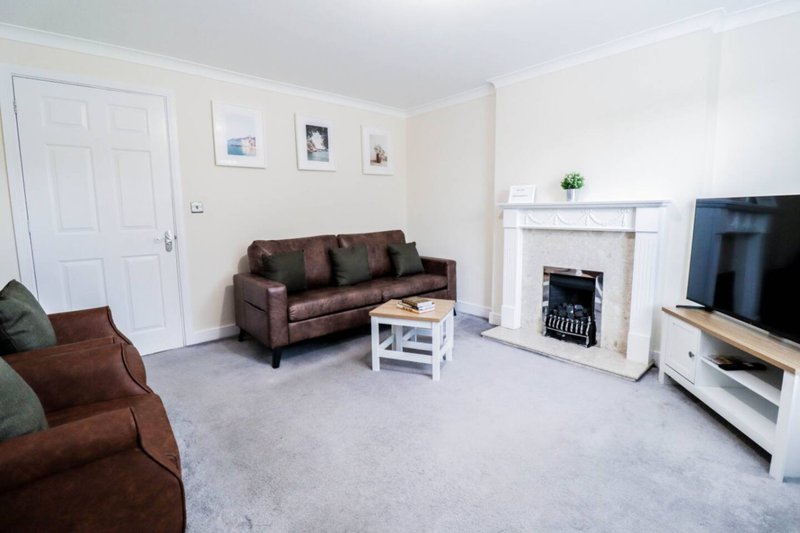 Spacious living room with brown sofa, fireplace, TV, and white doors