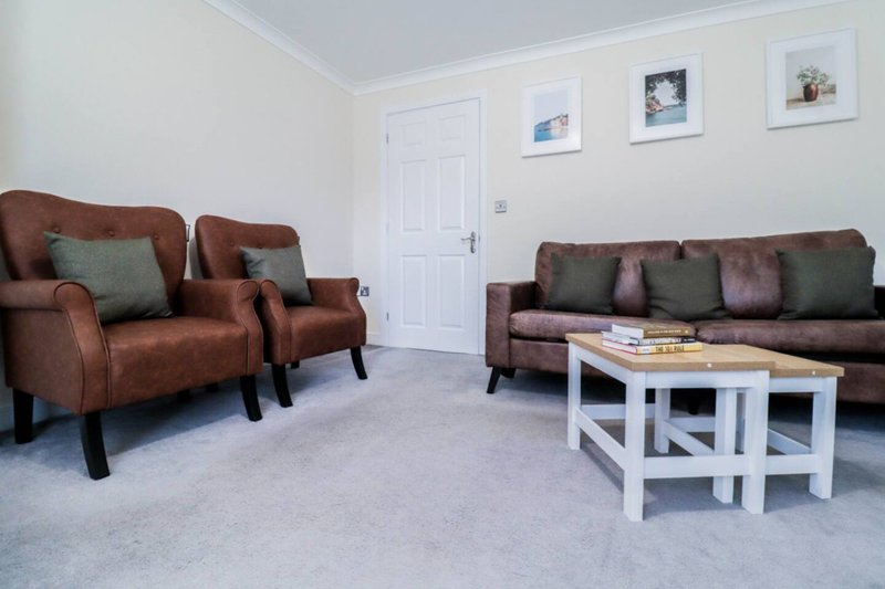 Spacious living room with brown leather armchairs, sofa, white coffee table and wall art