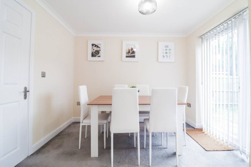 Dining room with wooden table, white chairs, framed wall art, and glass doors to garden