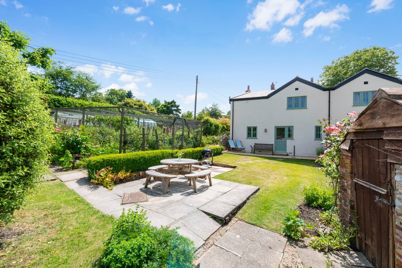 Modern house with garden, patio area, picnic table and surrounding green lawn