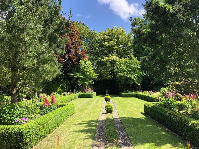 Manicured garden with lawn, hedges, flowering borders and mature trees