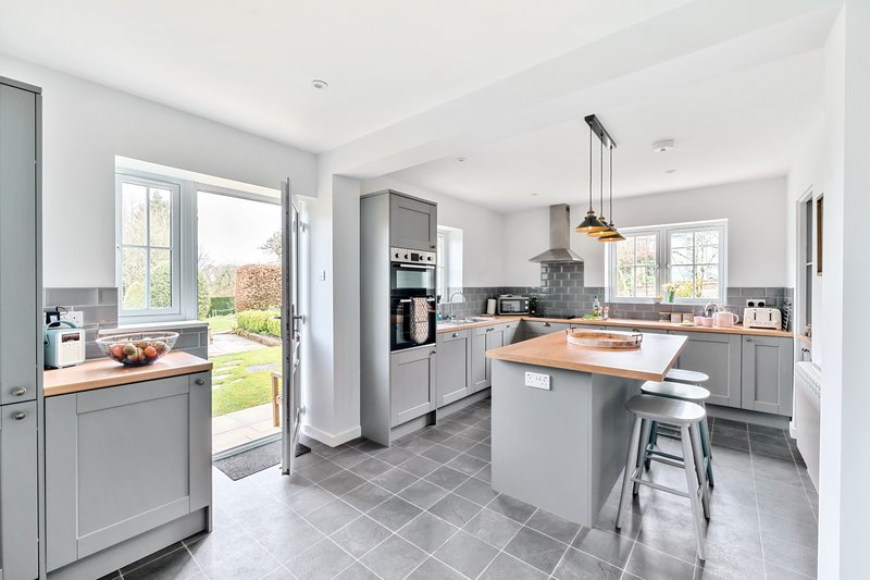 Modern kitchen with gray cabinetry, island seating, and open view to garden