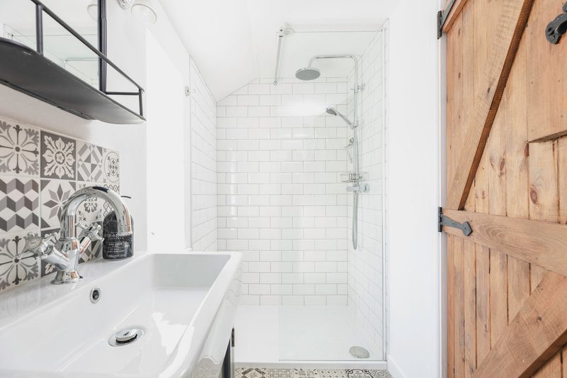 Modern bathroom with white subway tile, glass shower enclosure, sink and wooden door