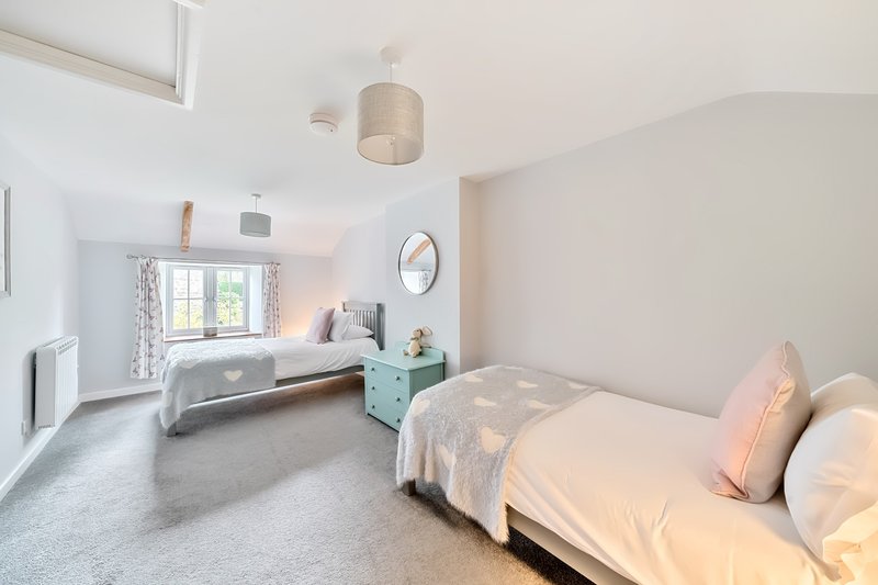 Bright bedroom with two single beds, turquoise nightstand, pendant light and window