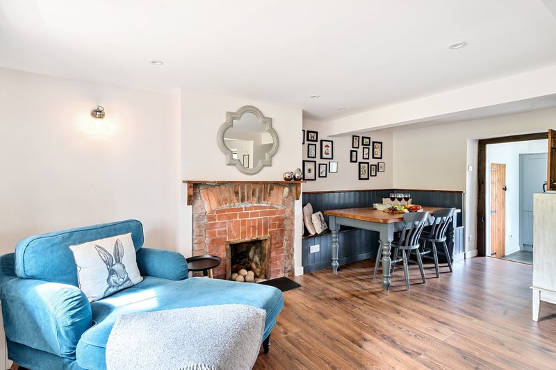 Open-plan living room with blue armchair, fireplace, dining area and hardwood floors