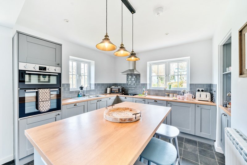Modern kitchen with gray cabinetry, wooden island, pendant lights and stainless steel appliances