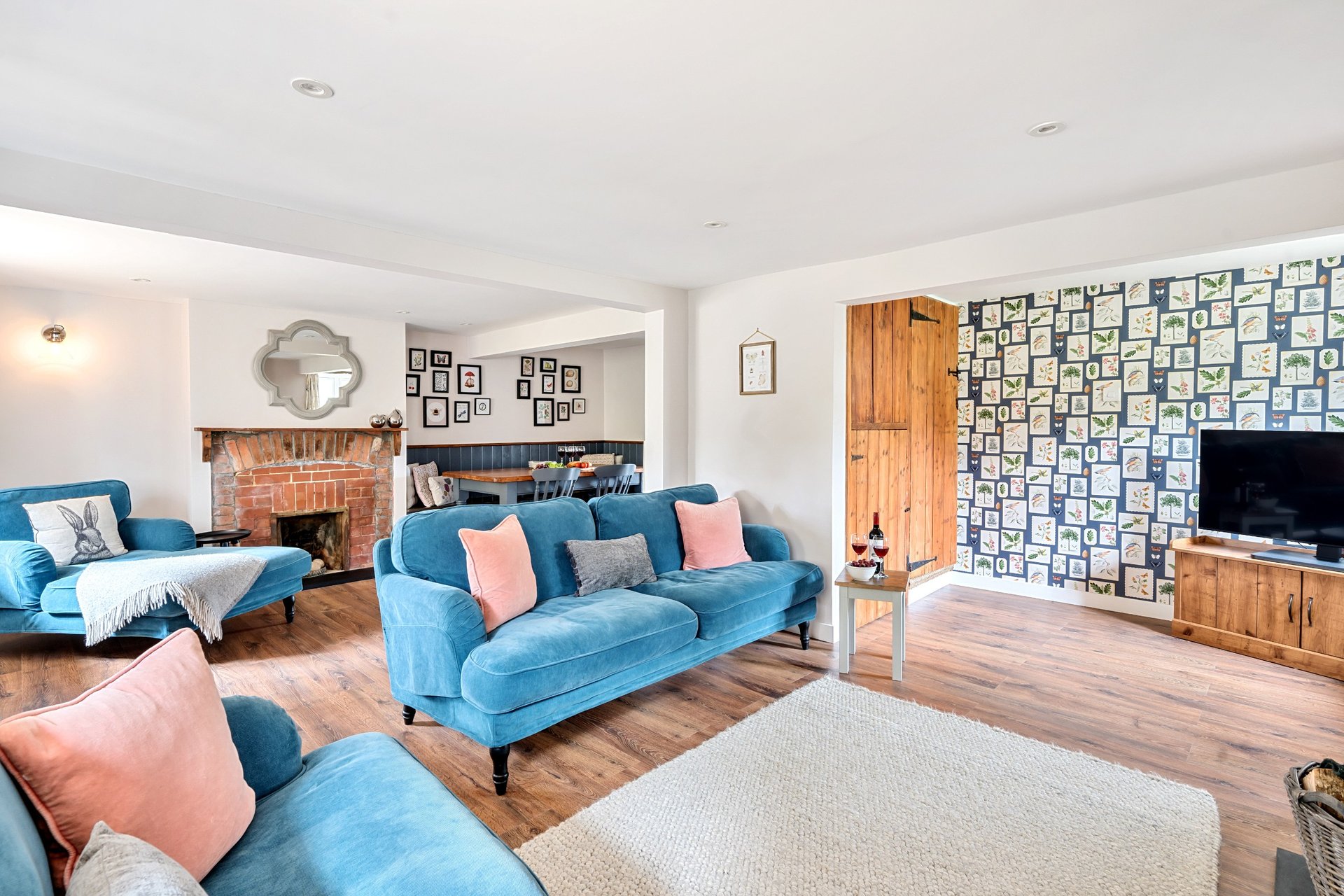 Spacious living room with blue sofas, fireplace, wooden furniture and gallery wall