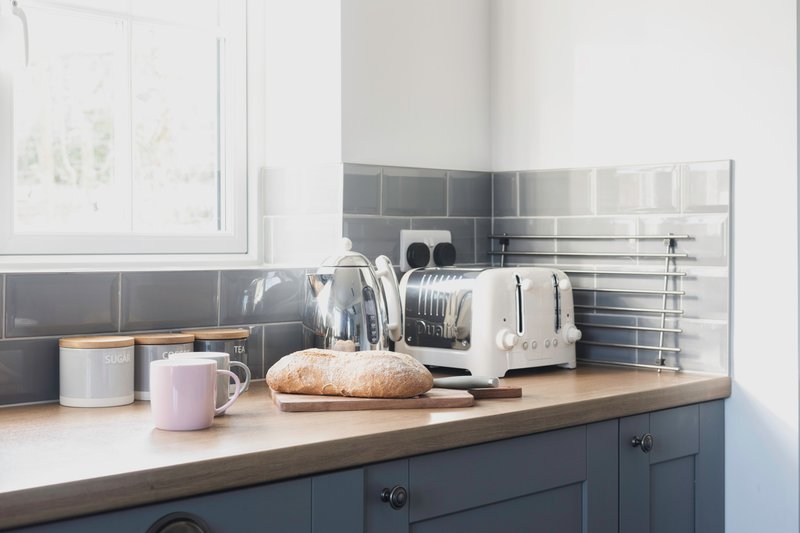 Modern kitchen countertop with white appliances, mugs, bread, and tableware on display
