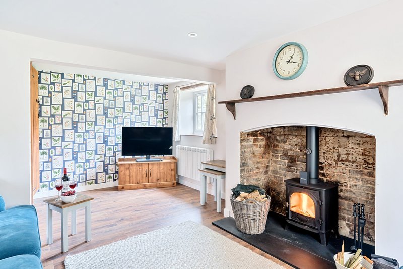 Bright living room with wood stove fireplace, blue patterned curtain, wall clock and decorative shelving