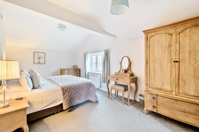 Bright bedroom with double bed, wooden furniture, dressing table and wardrobe