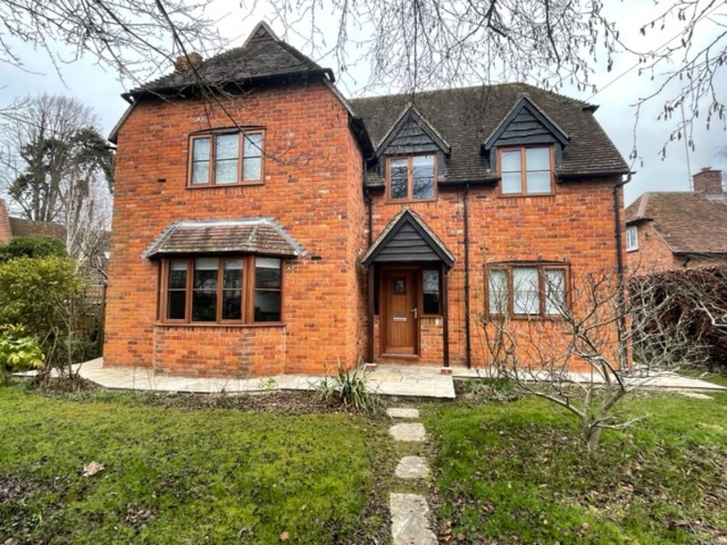 Brick detached house with pitched roof, front garden and entrance pathway