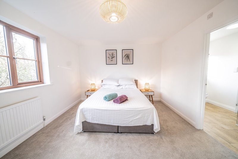 Bright bedroom with double bed, wooden floor, radiator and ceiling light