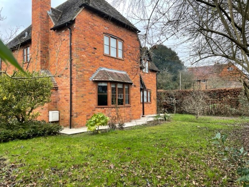 Red brick cottage with lawn, garden borders, and surrounding countryside views