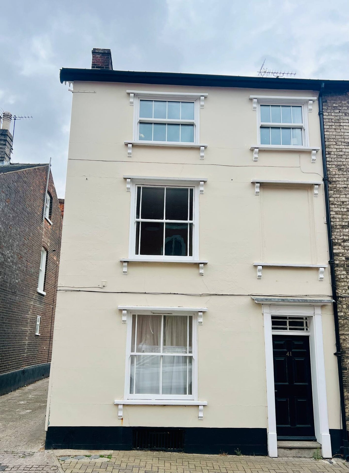 Cream and black multi-story townhouse exterior with regular windows and dark door