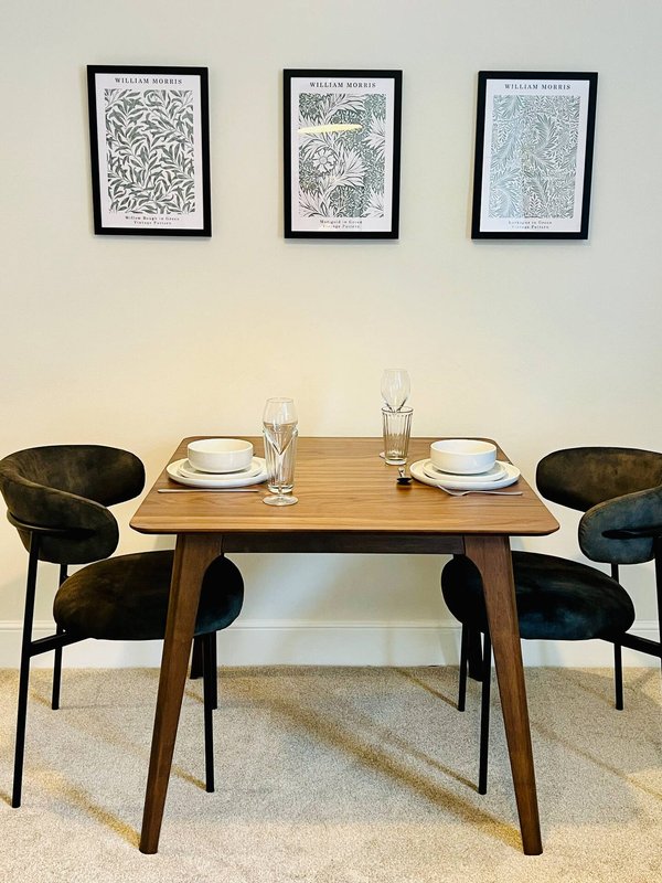 Dining room with wooden table, black chairs, place settings and framed wall art