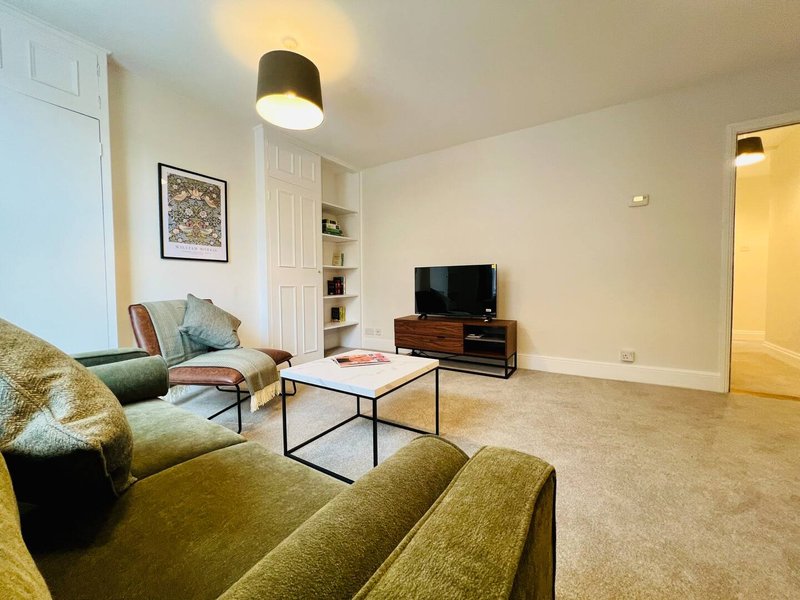 Spacious living room with green sofas, TV, coffee table, and framed wall art