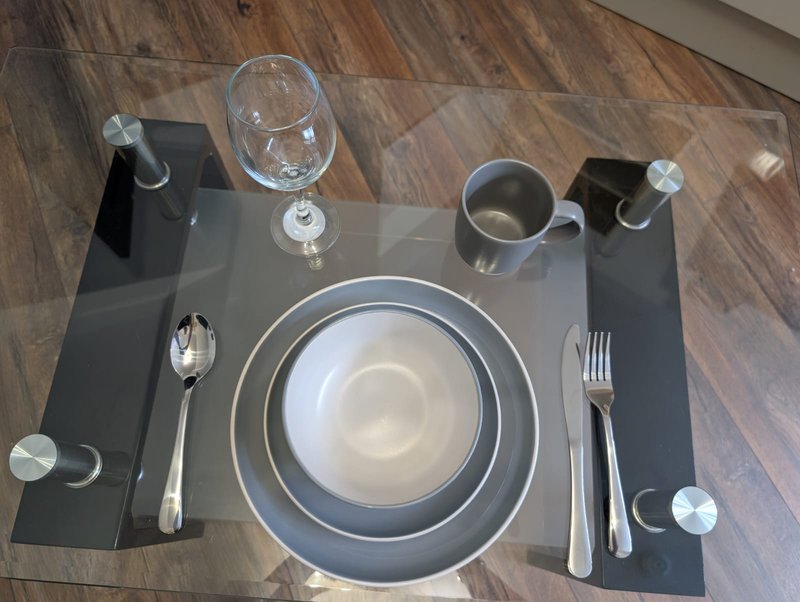 Overhead view of formally set dining table with plates, glasses, cutlery and napkins