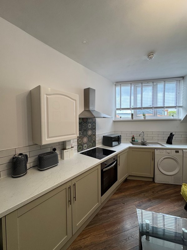 Modern kitchen with cream cabinetry, white countertops, black range cooker and window overlooking water