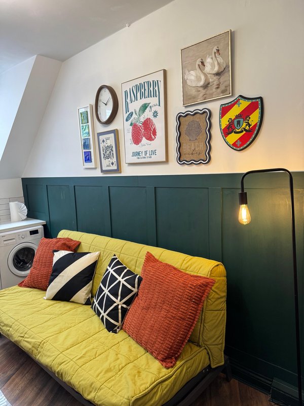 Bedroom with green upholstered headboard, yellow bedding, decorative pillows and wall art