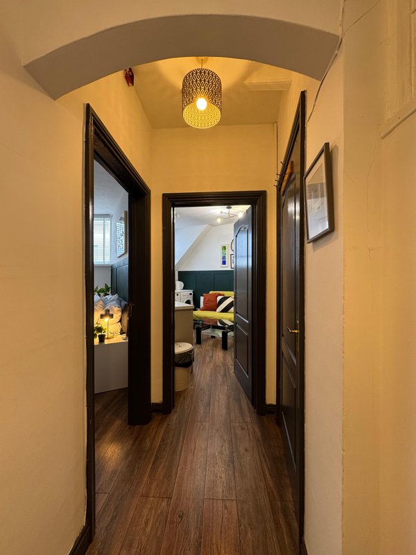 Hallway with cream walls, dark framed doorways, wooden flooring and ceiling light